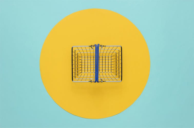 Mini shopping basket on blue background with yellow circle. Top view